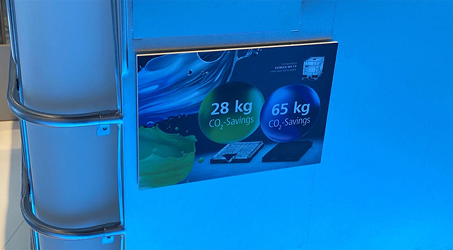 Billedet viser et udsnit af en IBC med et skilt, hvor man kan se CO2-besparelsen ved bæredygtig genanvendelse af industrielt plastaffald. Billedet er brugt til lederen i Plast og Emballages Medlemsinformation nr. 2-2023. Må IKKE bruges uden godk. fra bbi